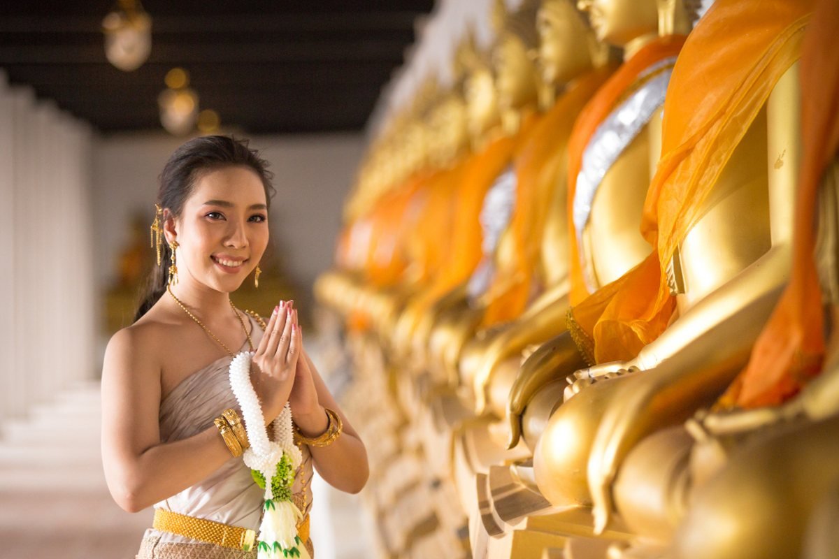 A Thai welcome, hands together in a wai, in traditional dress